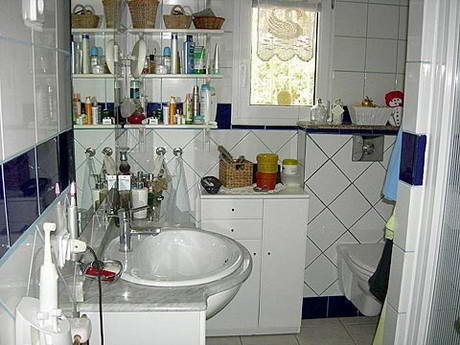 Salle de bain remplie  ras bord de flacons, parfums, dentifrice et brosses  dent, tout est sens dessus dessous