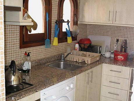 Cuisine avec gants de four pendouillant aux fentres et nombreux produits de nettoyage bien en vidence