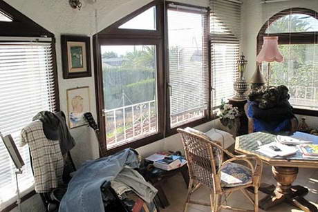 Terrasse couverte vitre avec un dsordre impressionnant, notamment des vtements usags jets ci et l sur des chaises