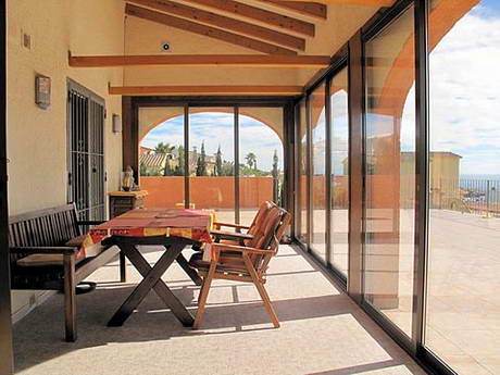 Terrasse couverte vitre (vranda) oriente vers la mer, mais avec un ciel partiellement couvert